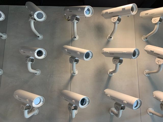 Various surveillance cameras in rows on a wall, each pointing to a different direction