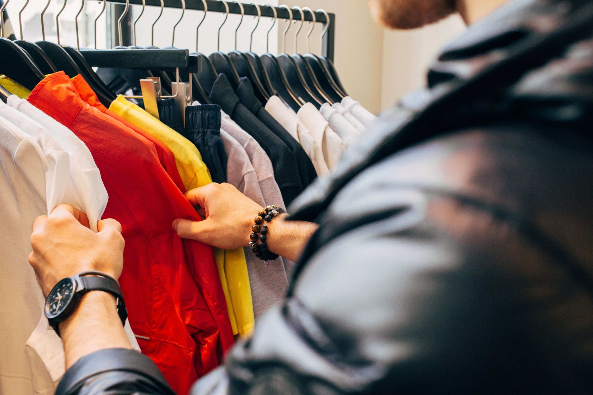 Man searching through different coloured shirts