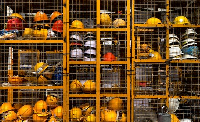 A metal cabinet with wired doors, storing construction safety helmets. Photo by Pop & Zebra on Unsplash
